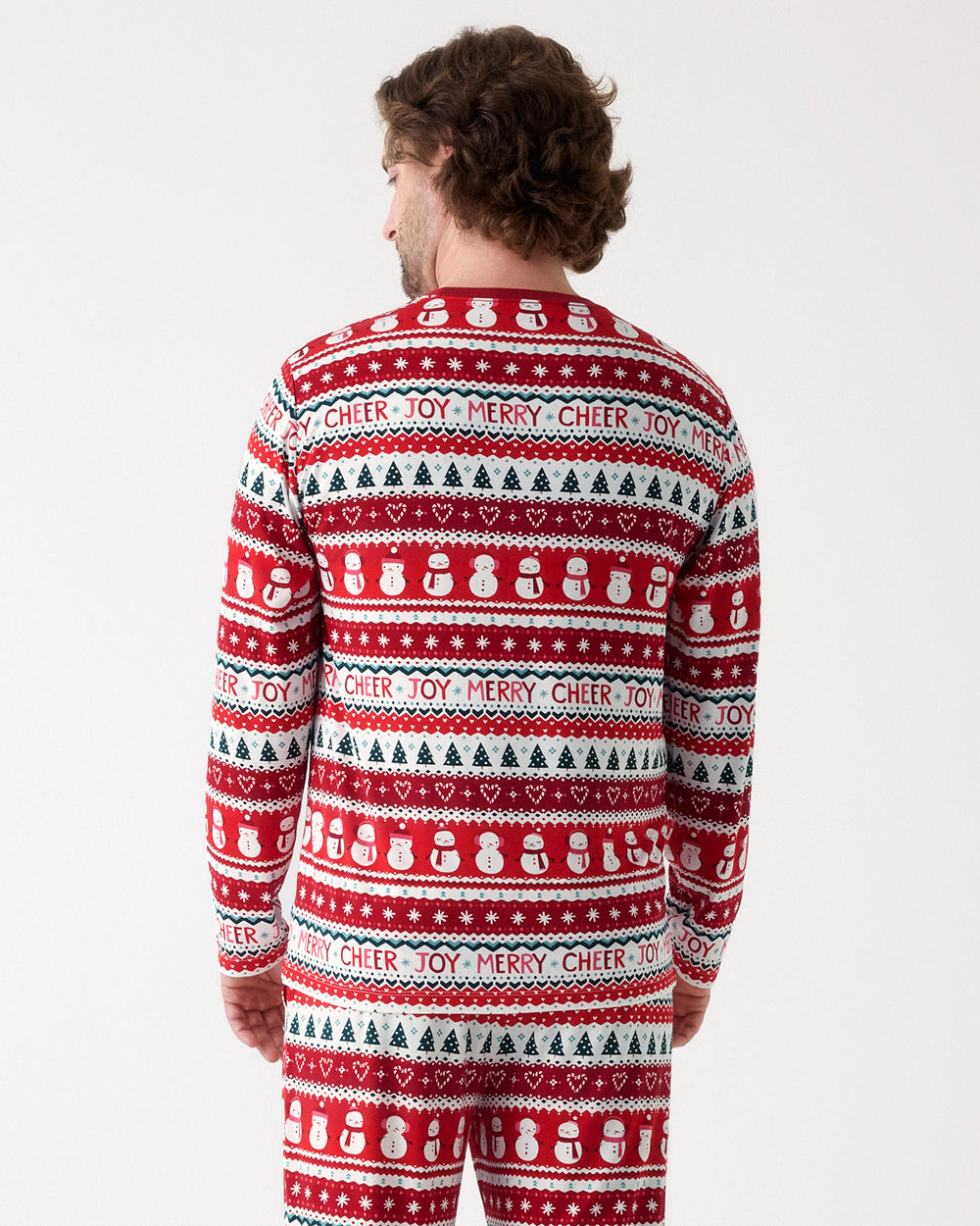 A man viewed from behind wearing a red and white Christmas-themed knit pajama set with 'CHEER MERRY' text and snowman patterns, against a light gray studio background.