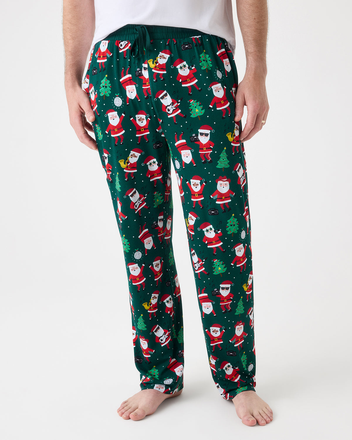 A person wearing dark green Christmas-themed pajama pants with an all-over Santa Claus print, shown from the waist down against a plain light background.