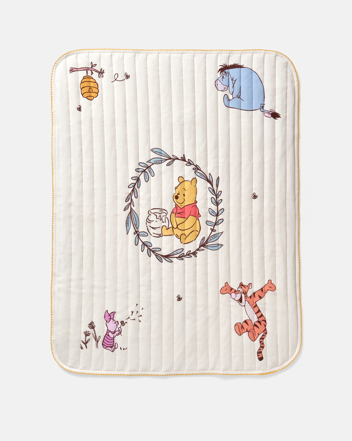 A square quilted baby blanket featuring Winnie the Pooh illustrations including Pooh, Tigger, Piglet, Eeyore, and a honeybee, on a cream background with a gold border.