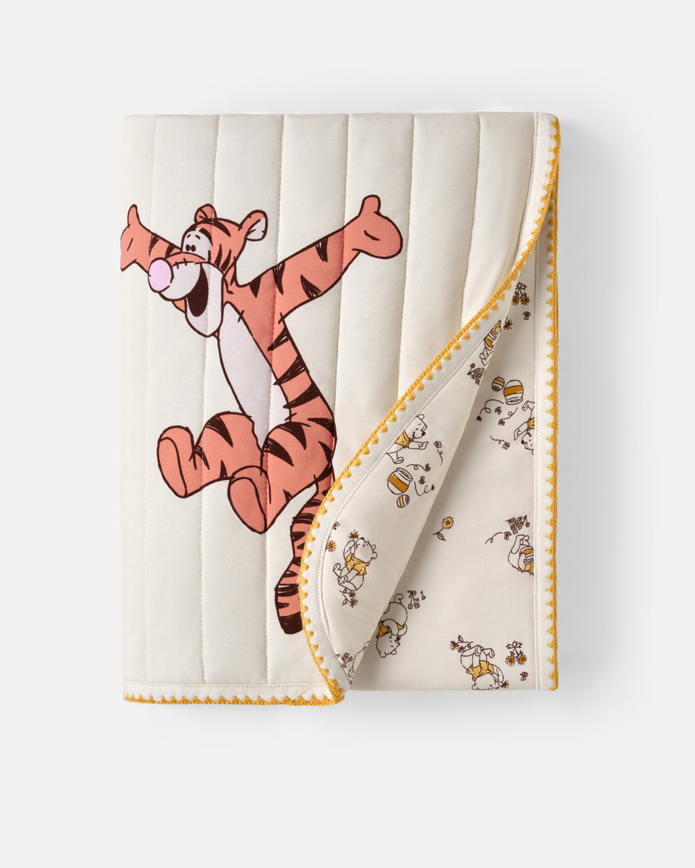 A quilted baby blanket featuring Winnie the Pooh Tigger on the front and a honeybee pattern on the reverse side, with a yellow zigzag stitched border, shown on a light gray background.