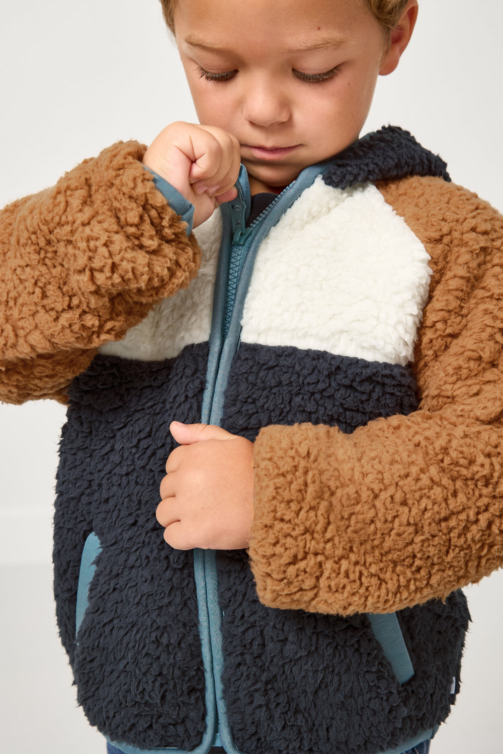 Child zipping up the Shadow Gray Sherpa Jacket