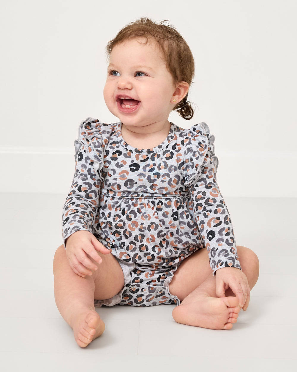 Sitting baby wearing the Snowy Leopard Bubble Romper