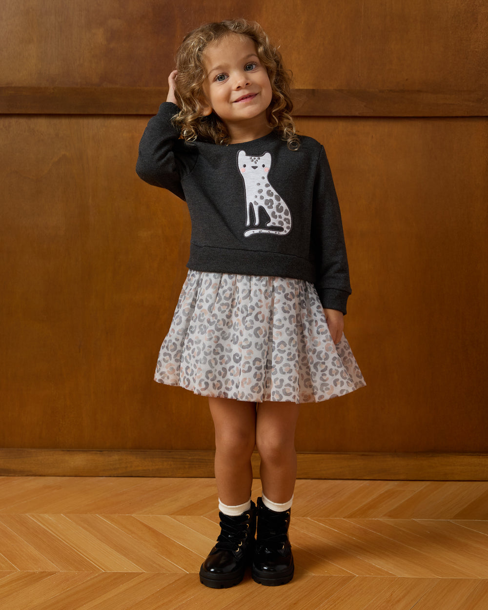 Girl wearing the Snowy Leopard Crewneck Tutu Dress on a wooden background