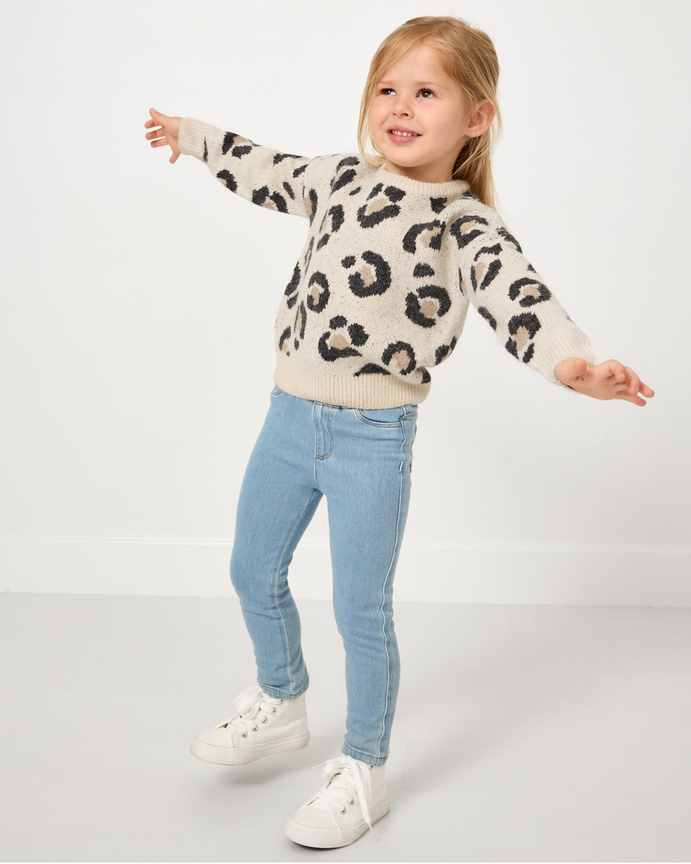 Posing girl wearing the Snowy Leopard Drop Shoulder Sweater with jeans