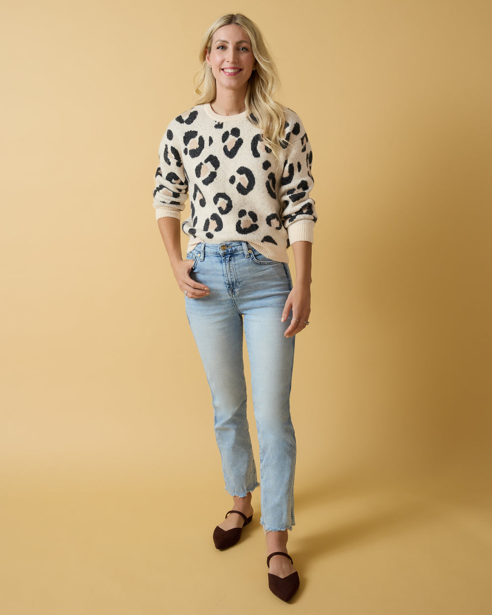 Woman wearing the Snowy Leopard Women's Drop Shoulder Sweater with jeans on a yellow background
