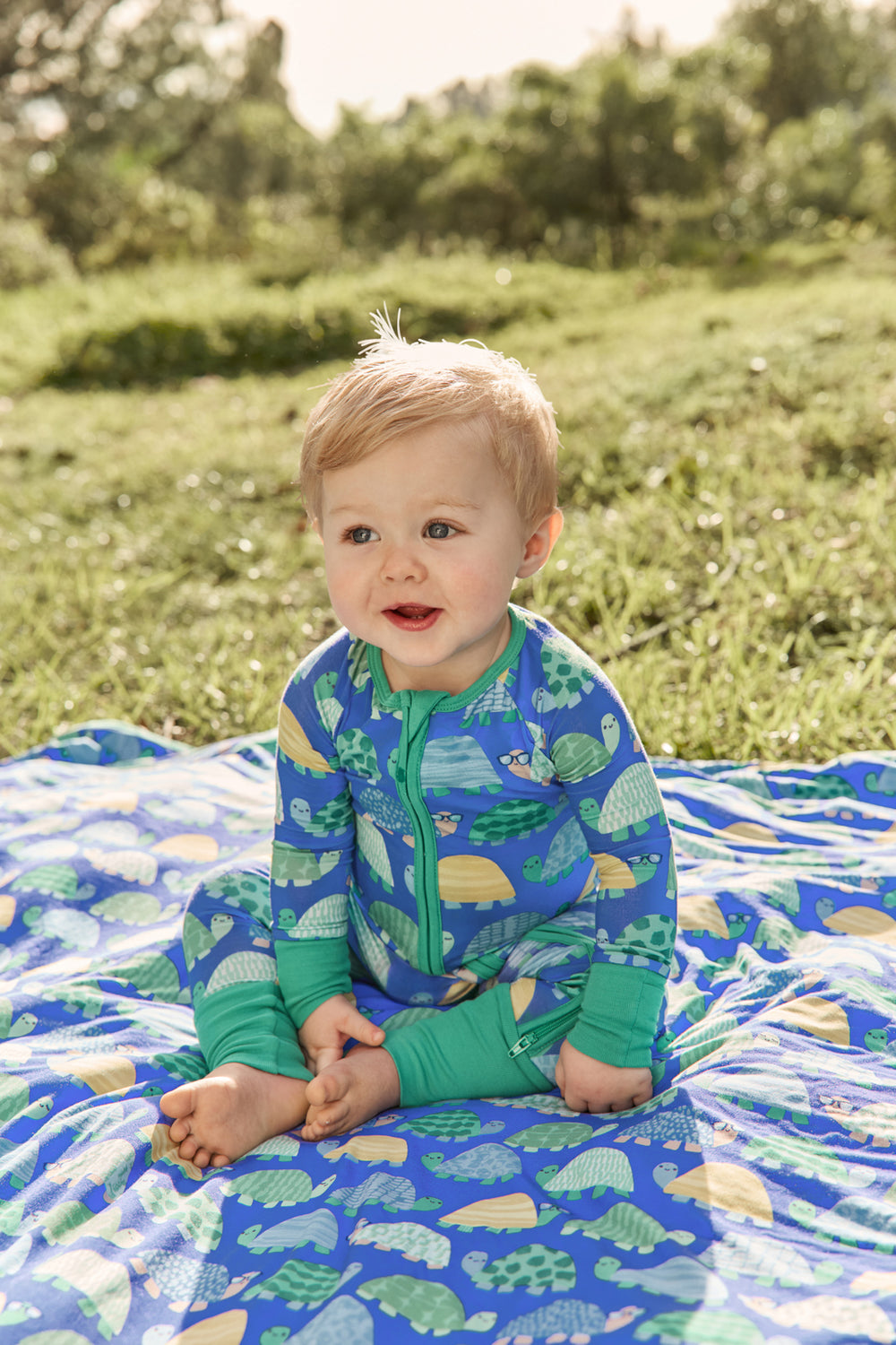 Baby boy wearing the Shell Parade Zippy sitting on a matching blanket