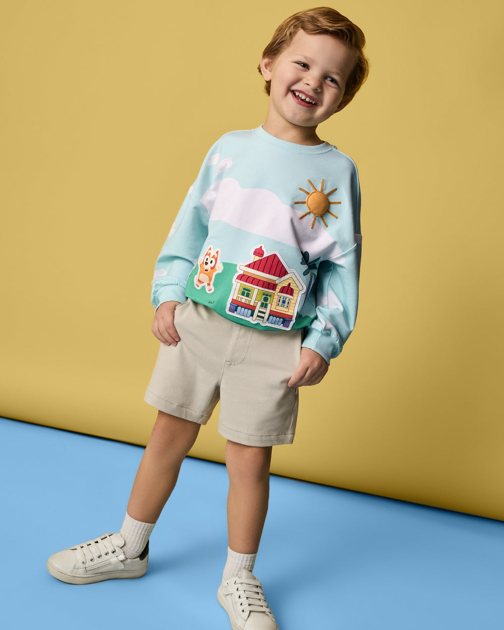 Boy wearing the Bluey The Heeler House Drop Shoulder Crewneck with khaki boys shorts