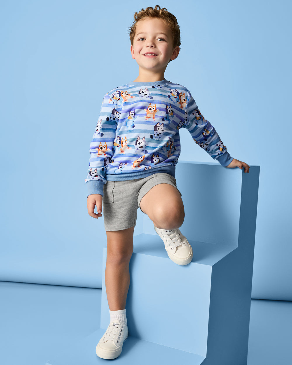 Boy wearing the Bluey Dance All Day Crewneck Sweatshirt on a blue background