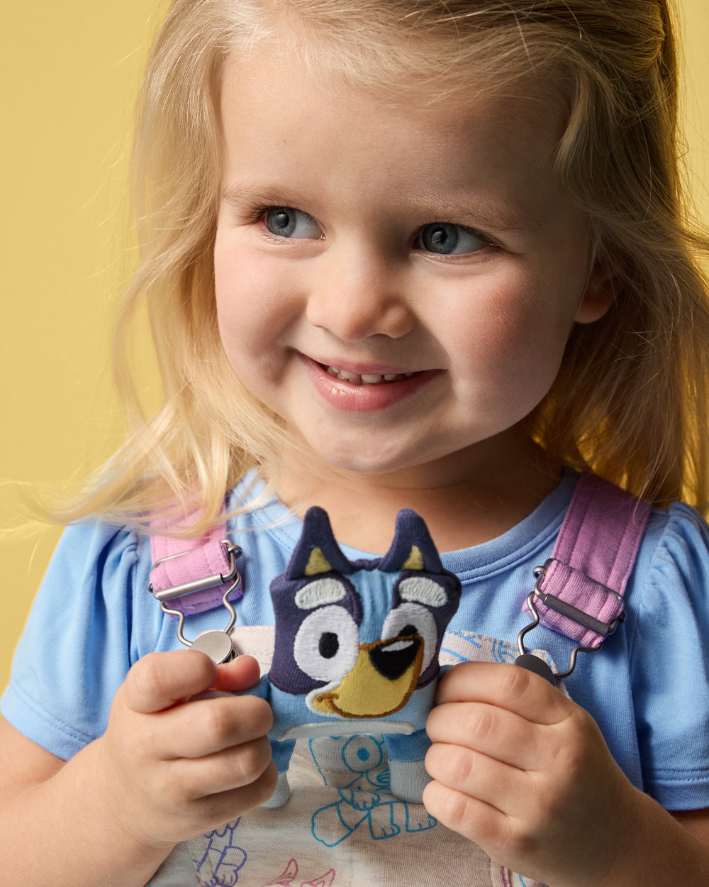 Close up of toddler wearing the Bluey Playtime Crew Skirt Overall over a blue puff sleeve tee