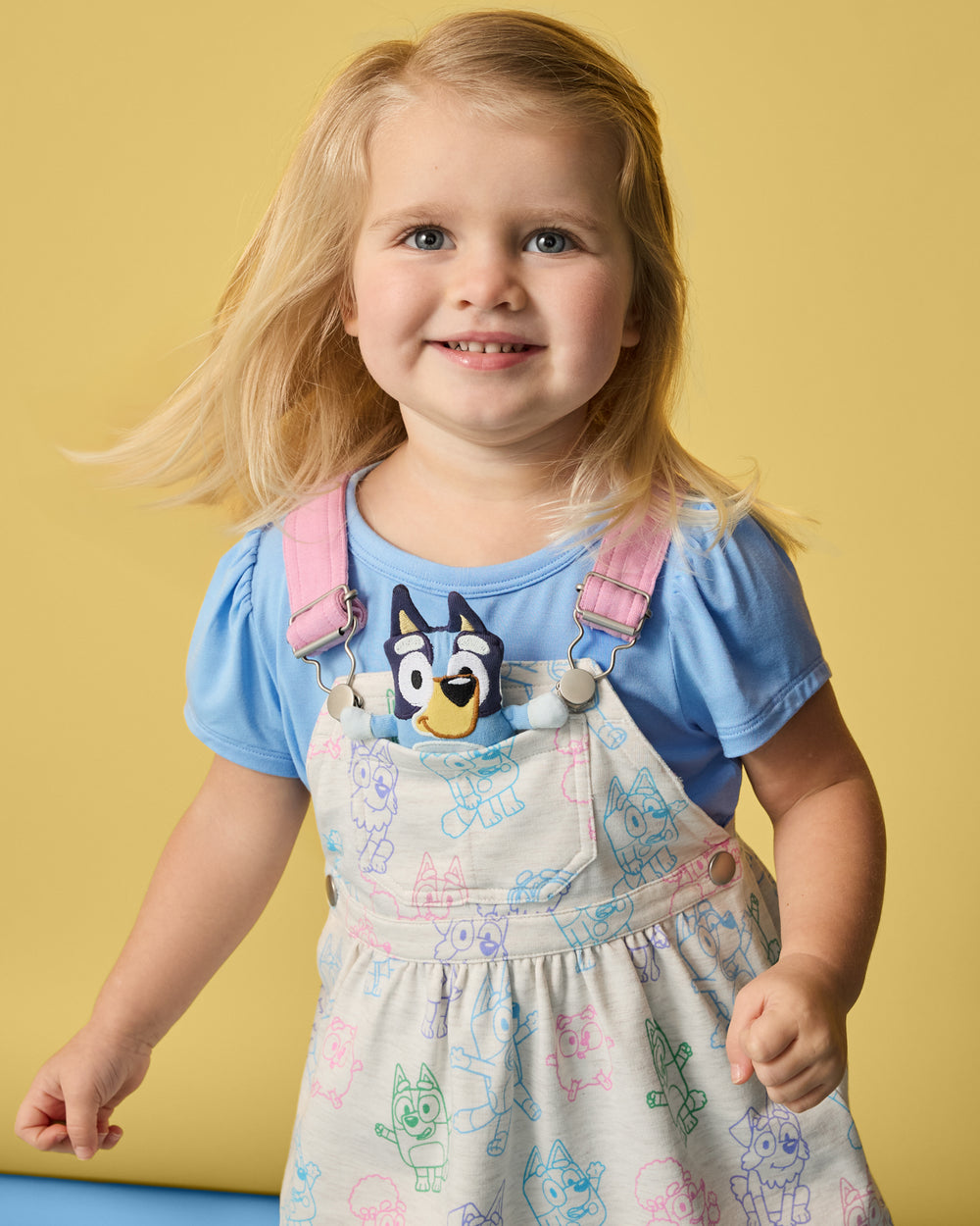 Girl wearing the Bluey Playtime Crew Skirt Overall over a blue tshirt