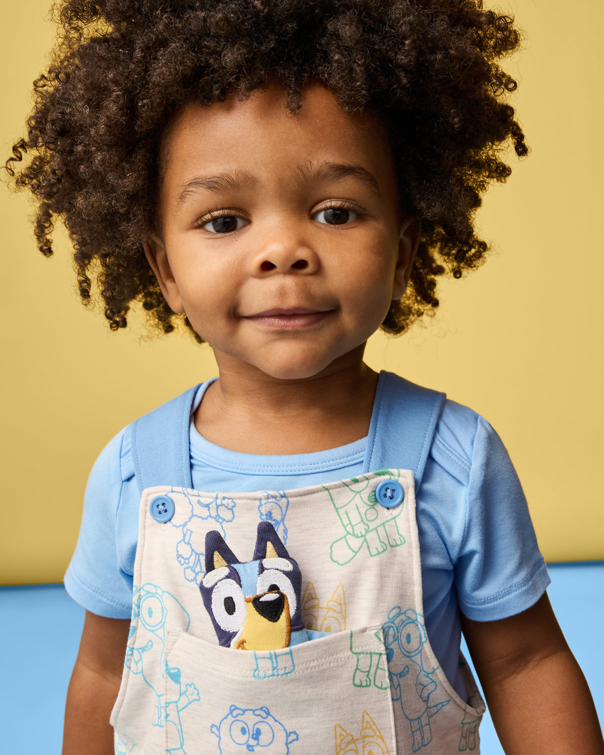 Close up of boy wearing the Bluey Playtime Crew Overall over a blue onesie
