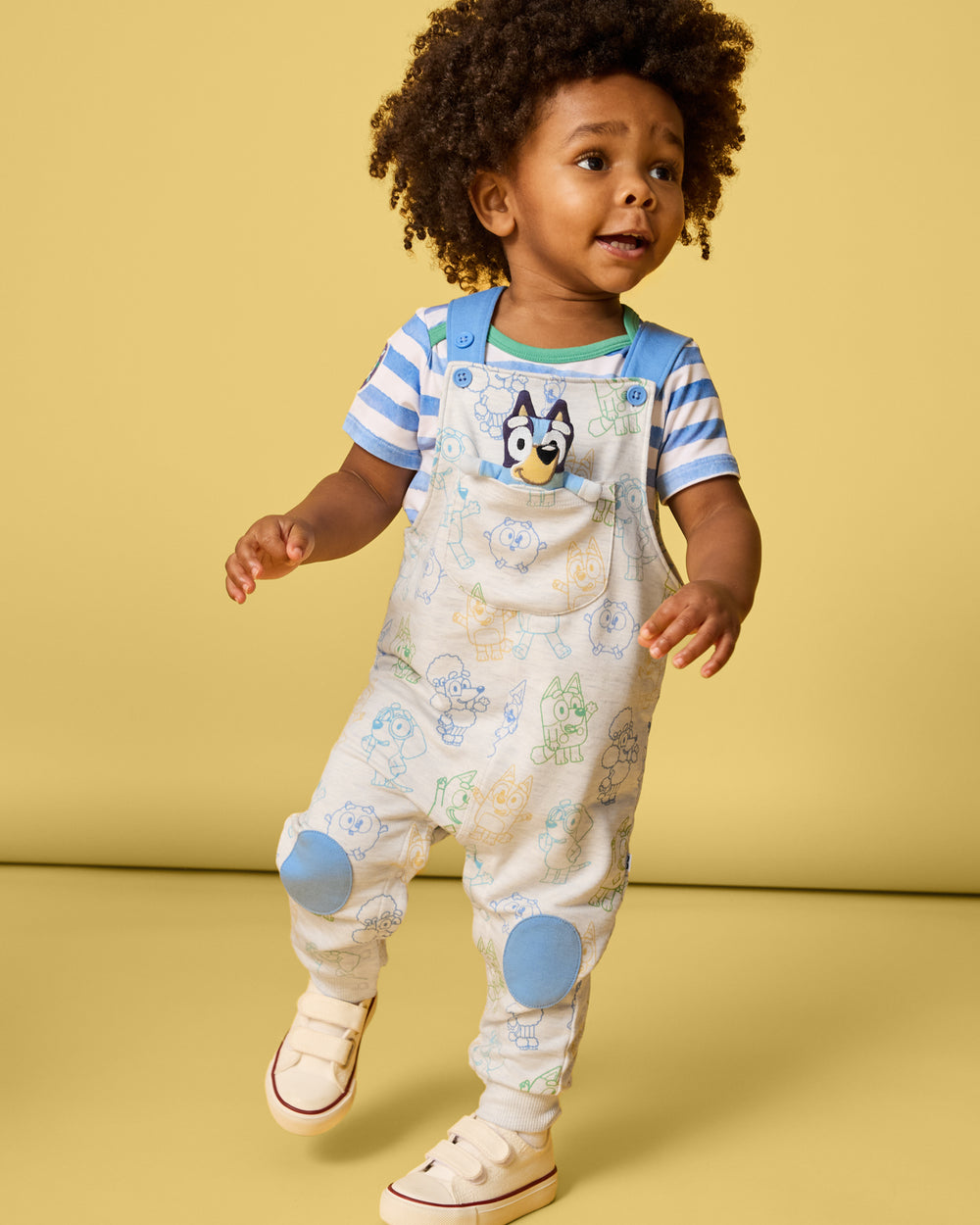 Boy wearing the Bluey Playtime Crew Overall on a yellow background