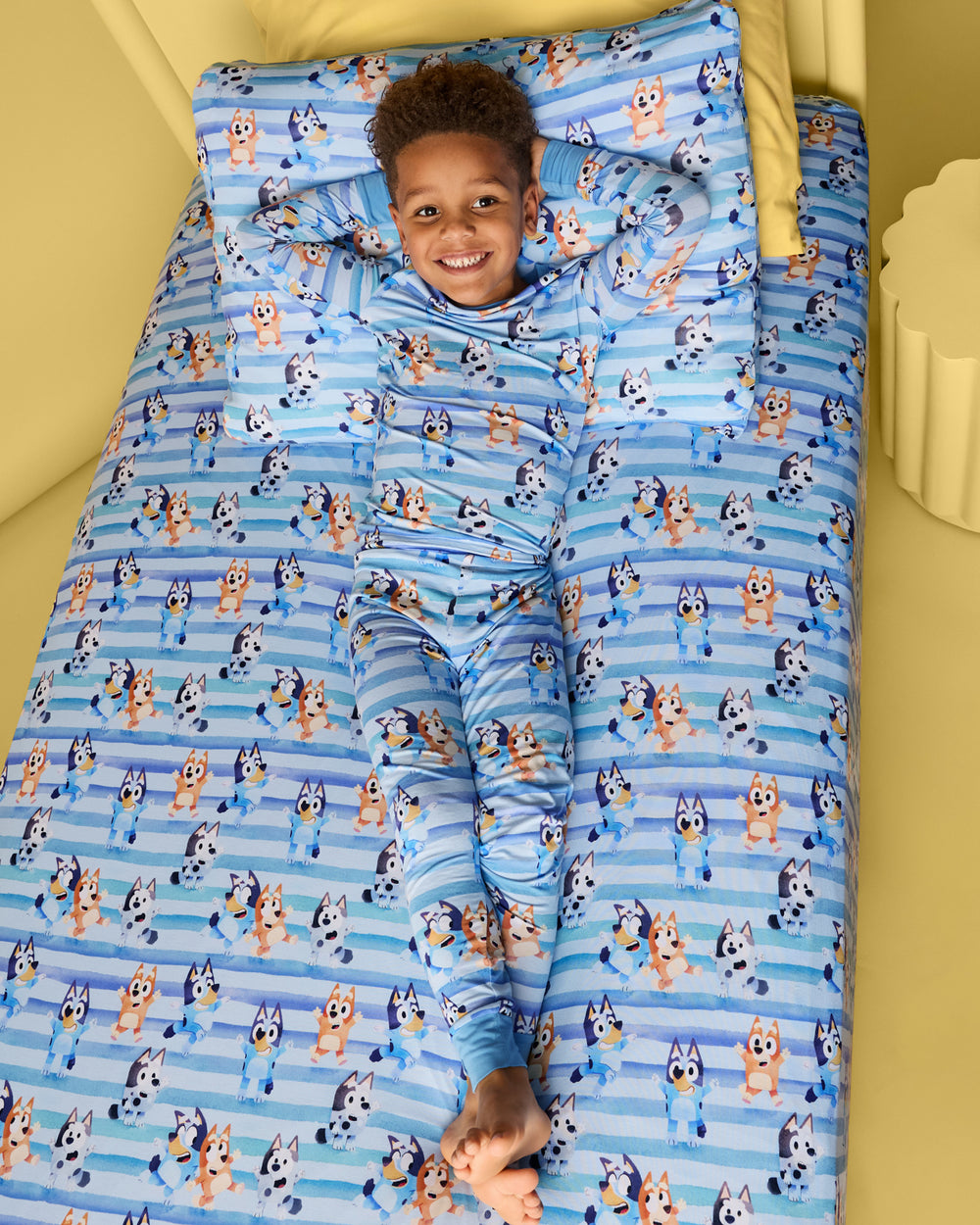 Child laying on a bed with the Bluey Dance All Day Twin Sheet Set