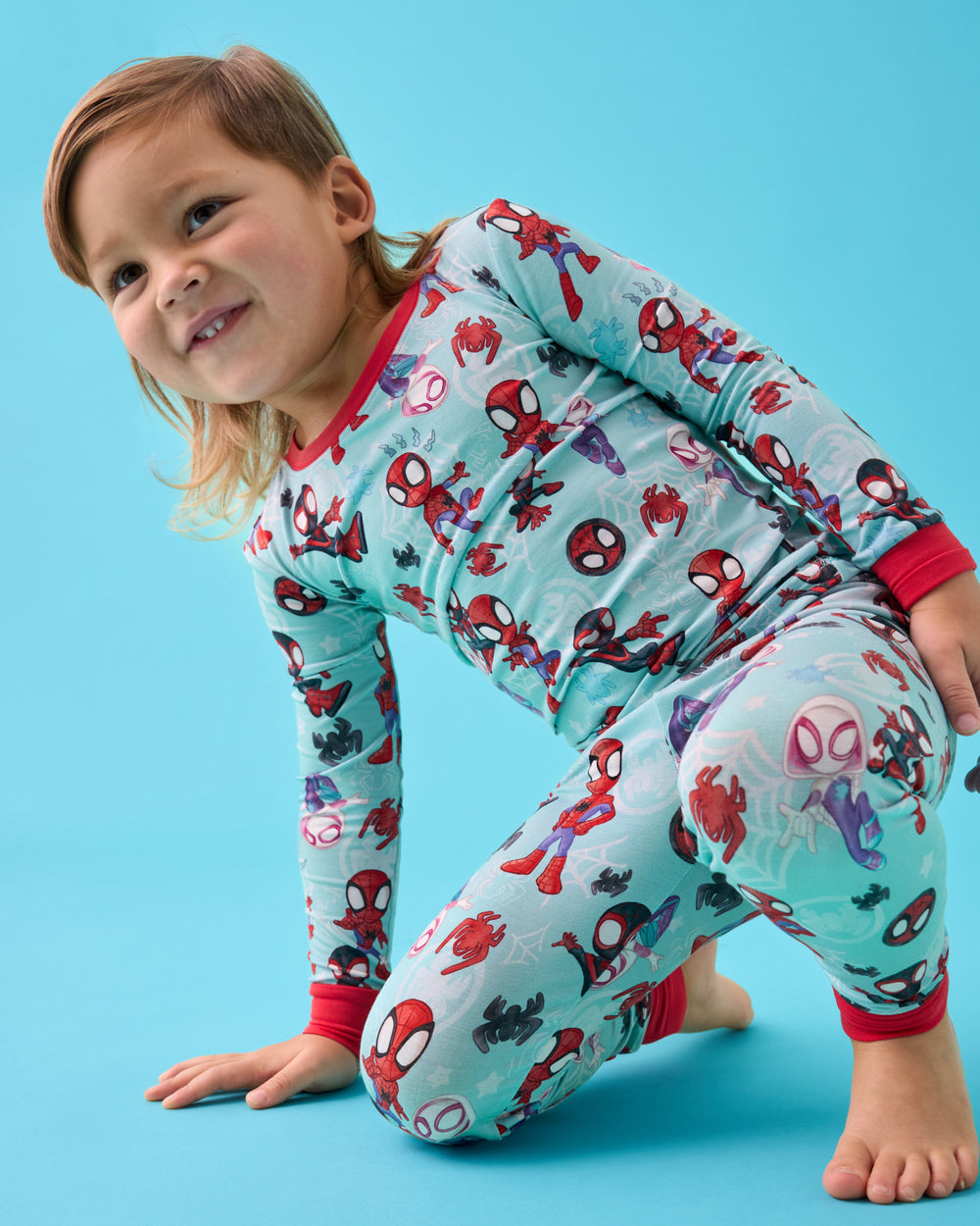 Boy wearing the Spidey & Friends Tiny Webs Two-Piece Pajama Set on a blue back drop
