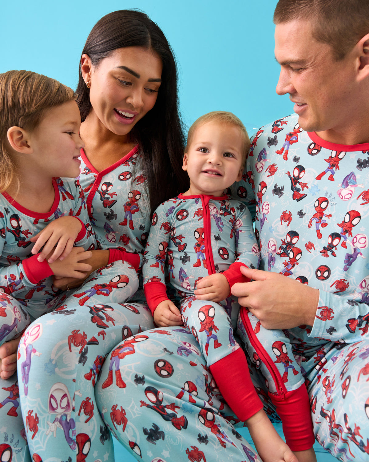 Family of four wearing matching Spidey & Friends Tiny Webs pajamas