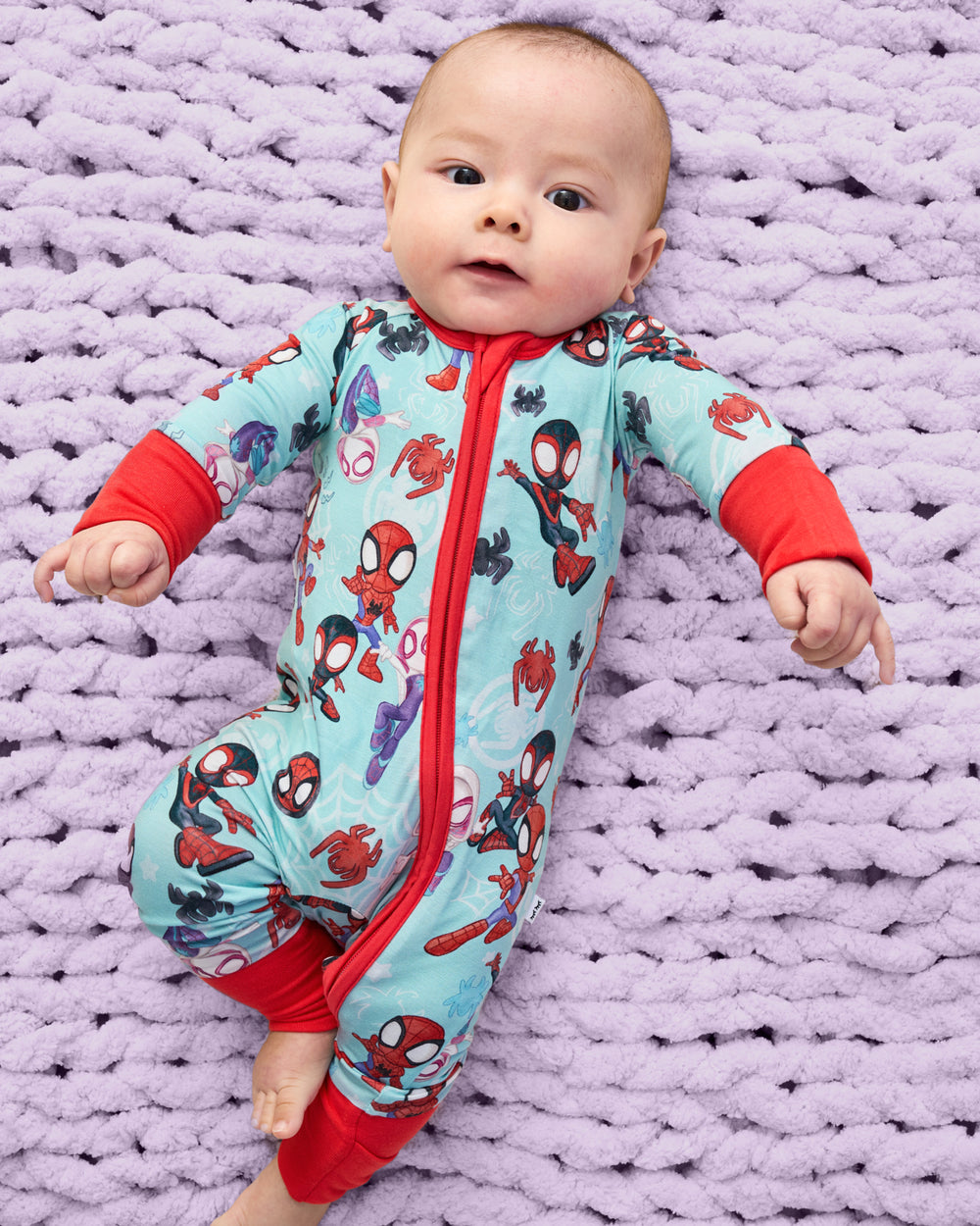 Baby wearing the Spidey & Friends Tiny Webs Zippy on a purple knit blanket