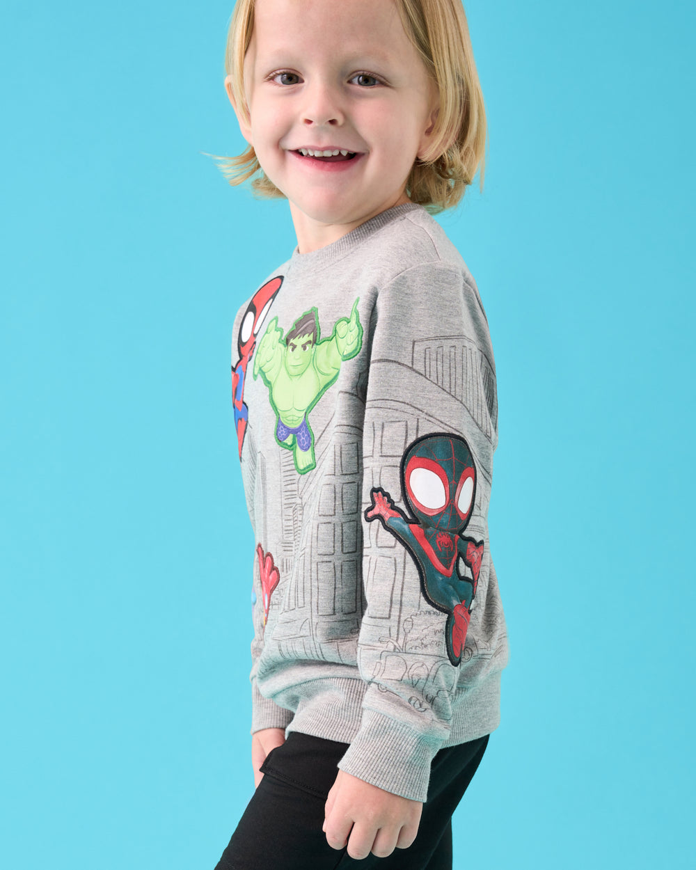 Boy wearing the Spidey & Friends Mighty City Heroes Crewneck Sweatshirt on a blue back drop