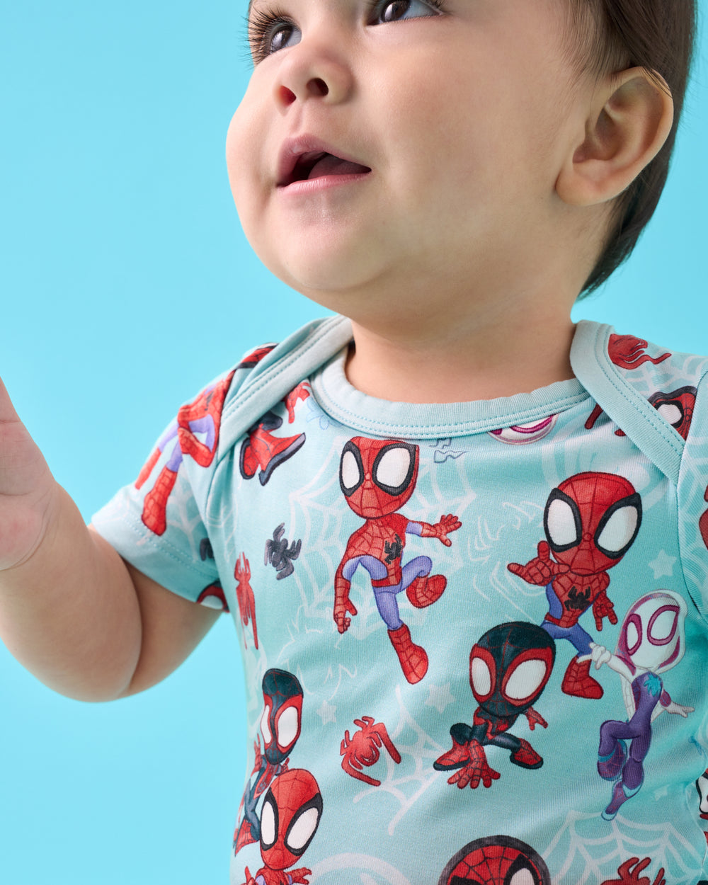 Close up of baby wearing the Spidey & Friends Tiny Webs Short Sleeve Bodysuit on a blue back drop