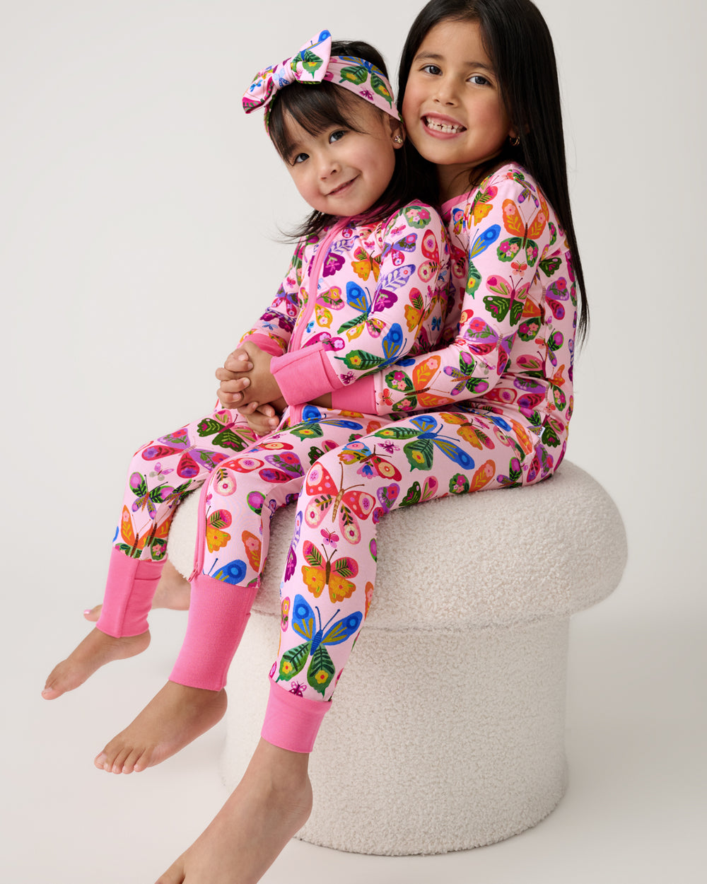 Two girls wearing matching Flutter Garden butterfly print pajamas