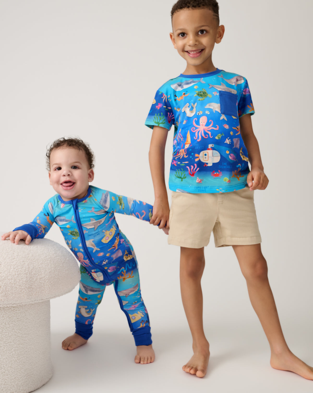 Two children wearing matching Underwater Discovery sleep and play styles