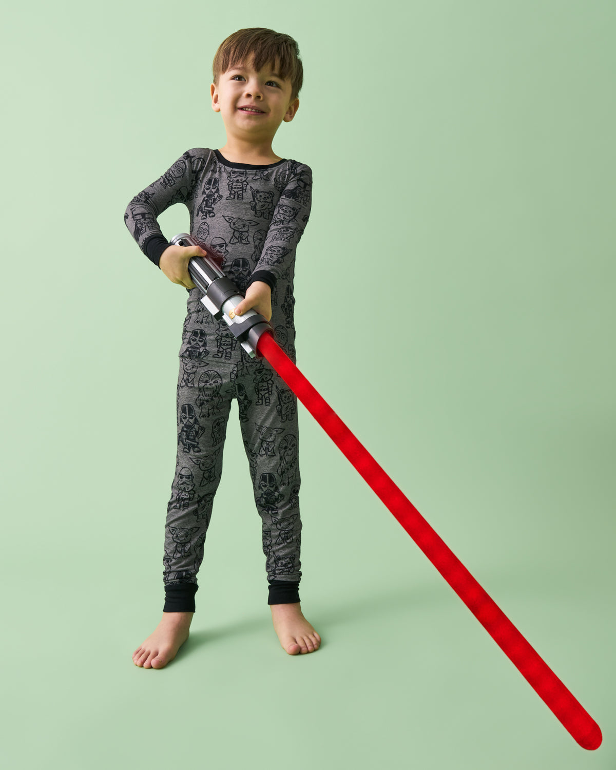 Boy holding a lightsaber wearing the Star Wars Far, Far Away Friends Two-Piece Pajama Set