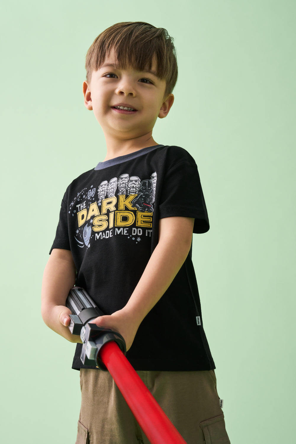 Boy wearing the Star Wars Dark Side Relaxed Tee holding a red lightsaber