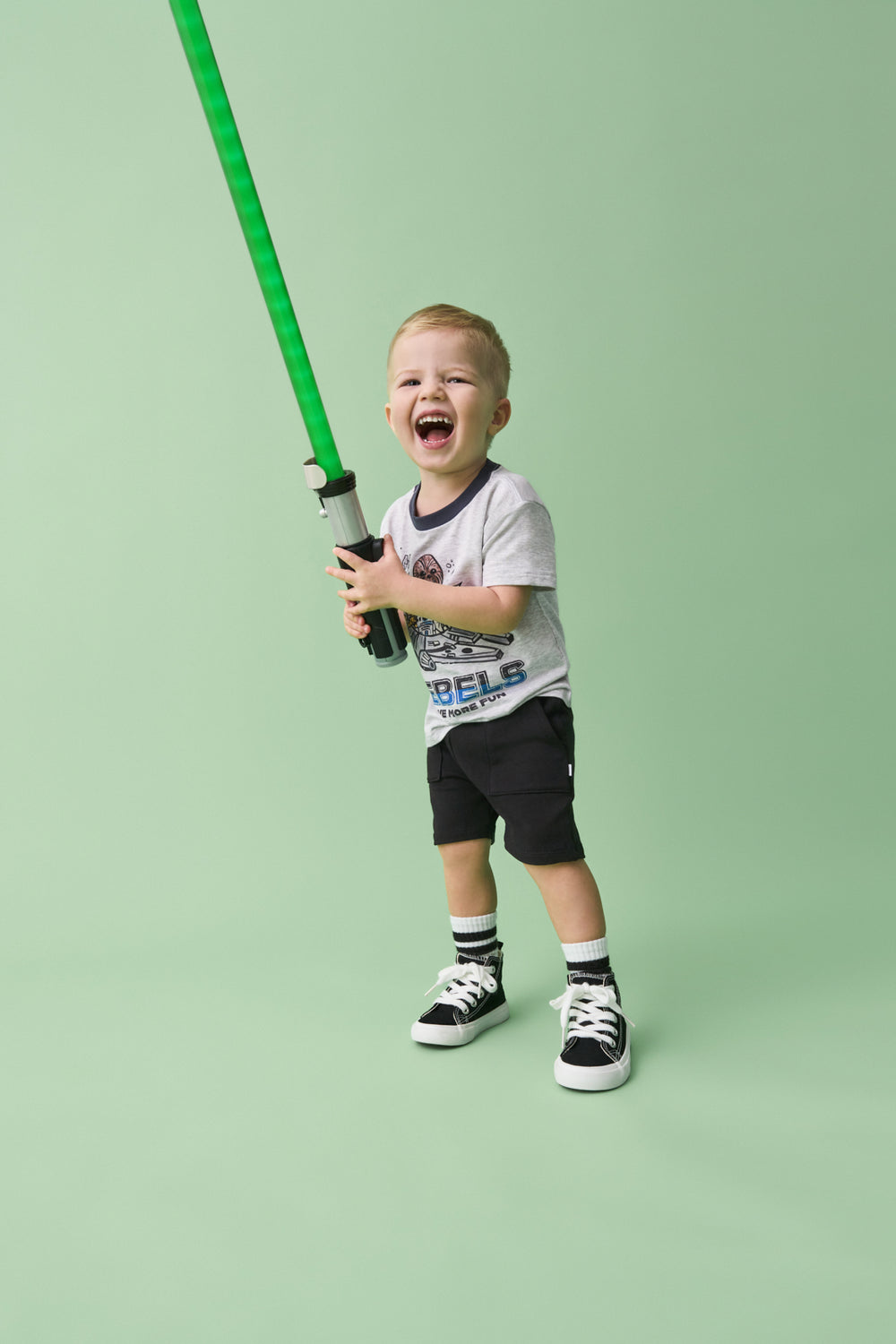 Boy wearing the Star Wars Little Rebels Relaxed Tee holding a green lightsaber