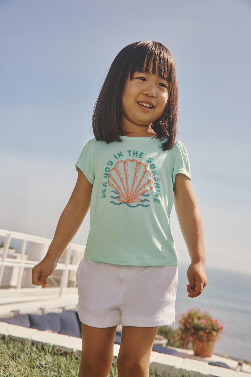 Girl wearing the Sparkling Seas Puff Sleeve Tee in a backyard