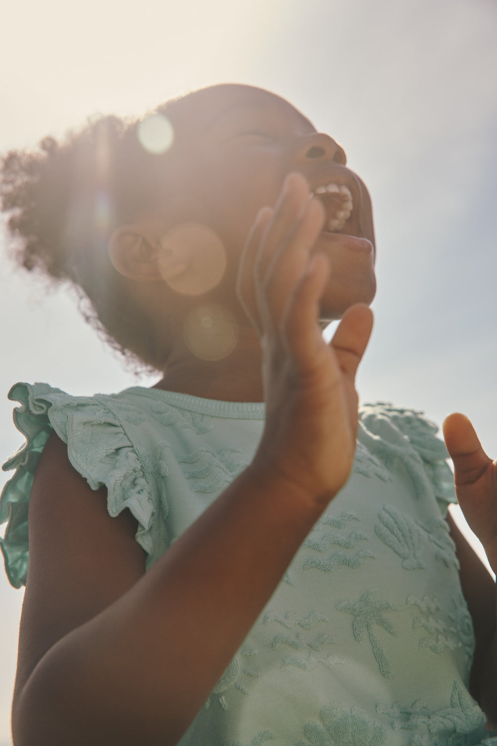 Close up of girl wearing the Coastal Rays Bow Front Flutter Top with a sky backdrop