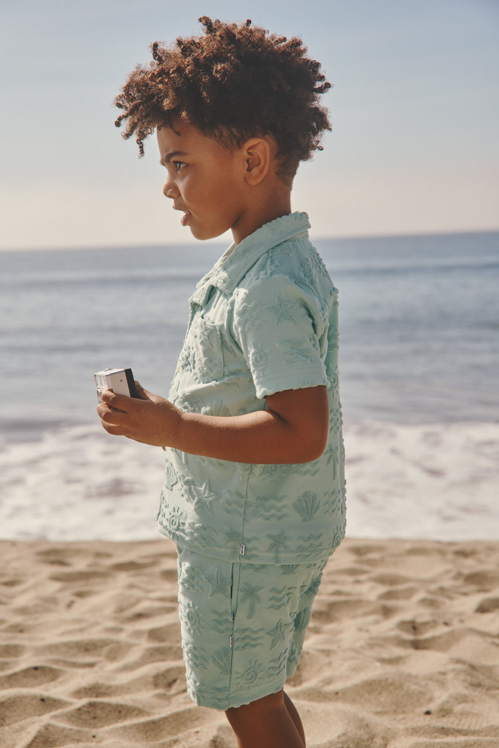 Boy wearing the Coastal Rays Button Down Polo and Shorts at the beach