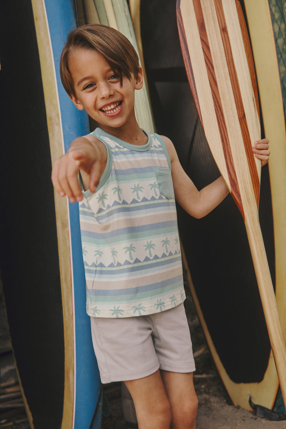 Boy wearing the Swell Stripes Pocket Tank with surfboards in the background
