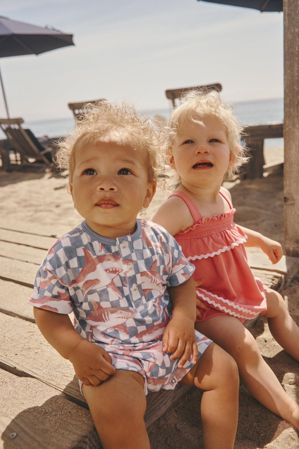 Two children sitting on a deck wearing Summer Daywear styles 