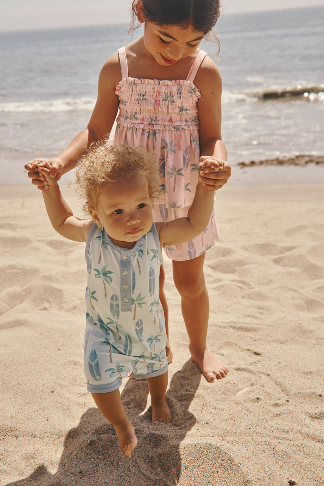 Two children on a beach wearing matching Palm Dunes summer styles