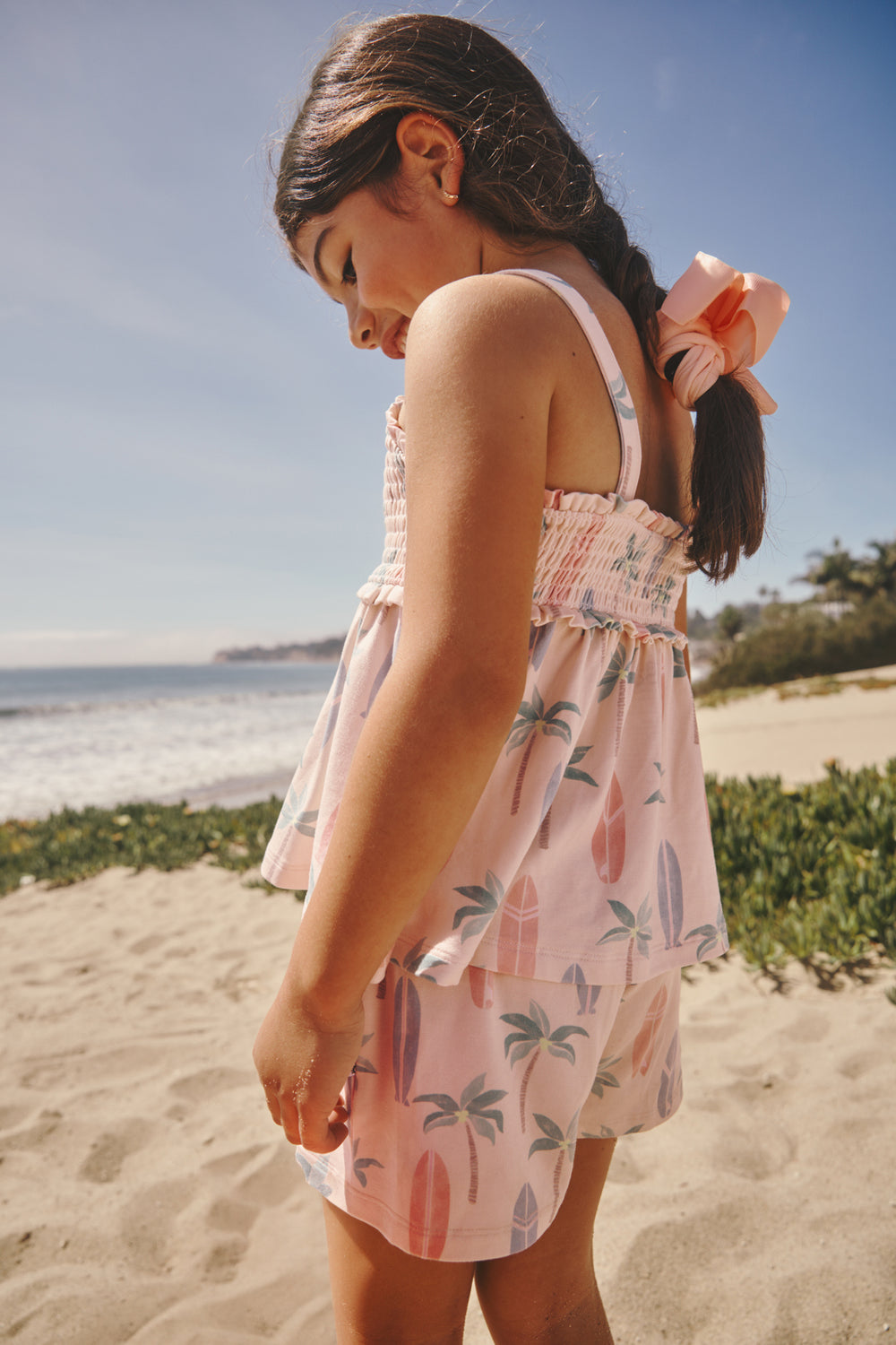 Girl wearing the Palm Dunes Smocked Tank & Shorts Set with a beach in the background