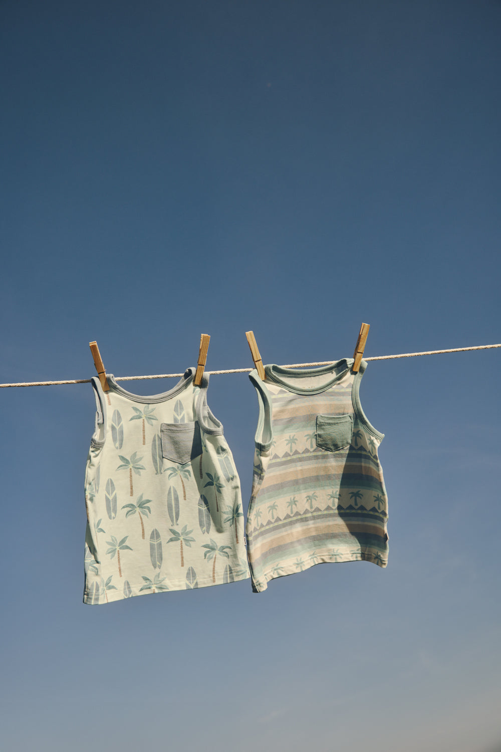 Two summer boys tanks hanging on a clothes line