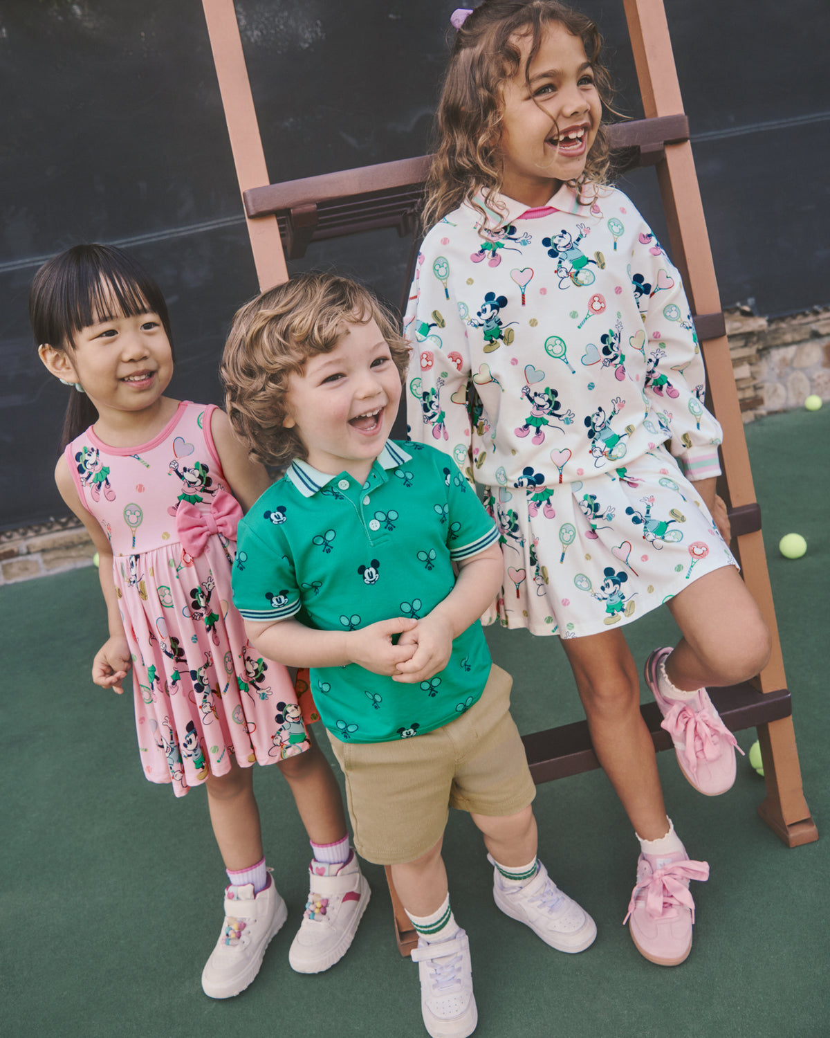 Three children wearing Disney Mickey Mouse Varsity Play styles on a tennis court