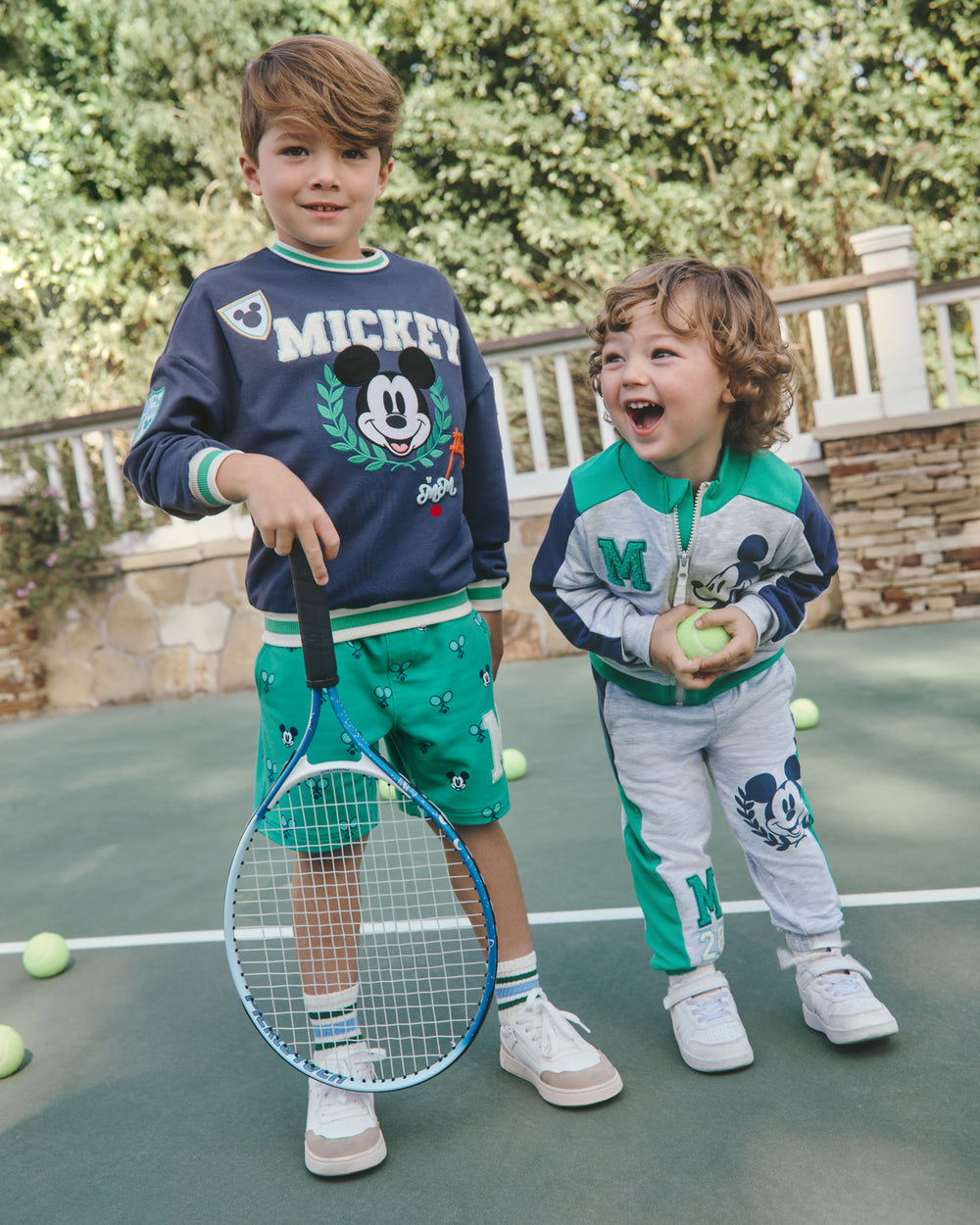 Two boys wearing Disney Mickey Mouse Sports Club Varsity styles on a tennis court