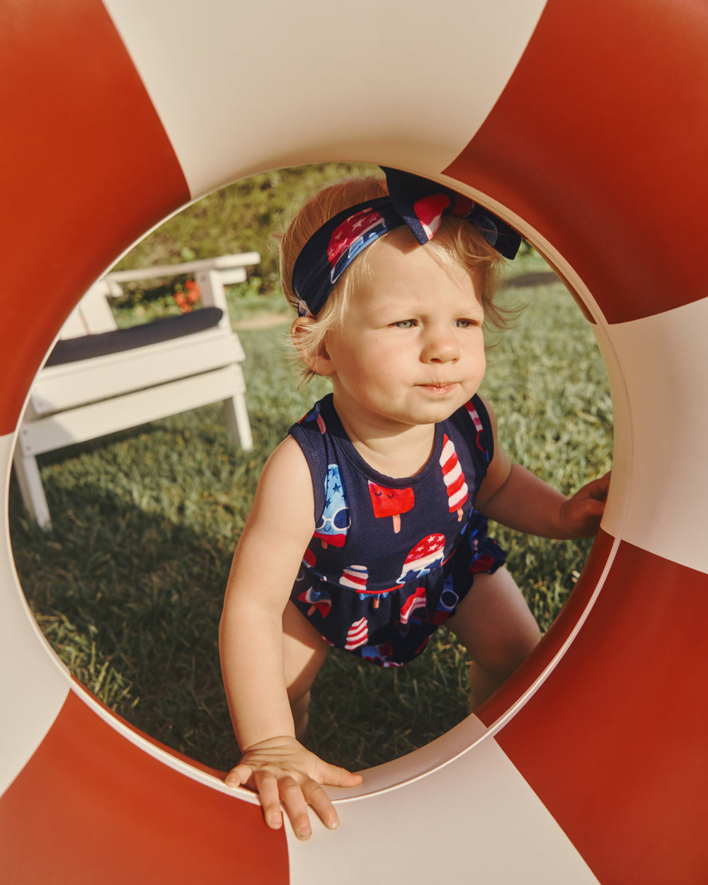 Girl wearing the Sparkle Treats Bubble Romper leaning on a striped tube