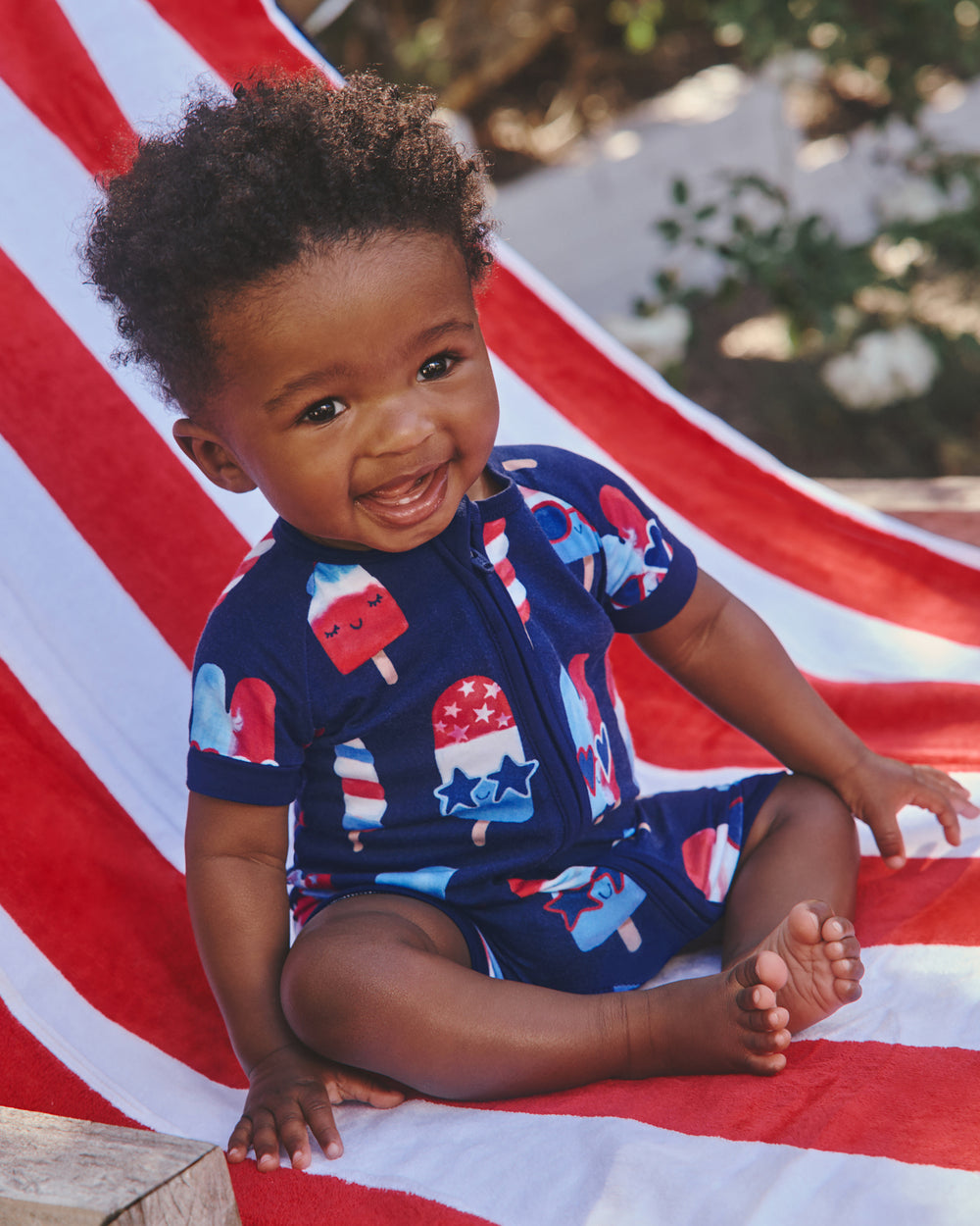 Baby wearing the Sparkle Treats Shorty Zippy on a red and white striped towel