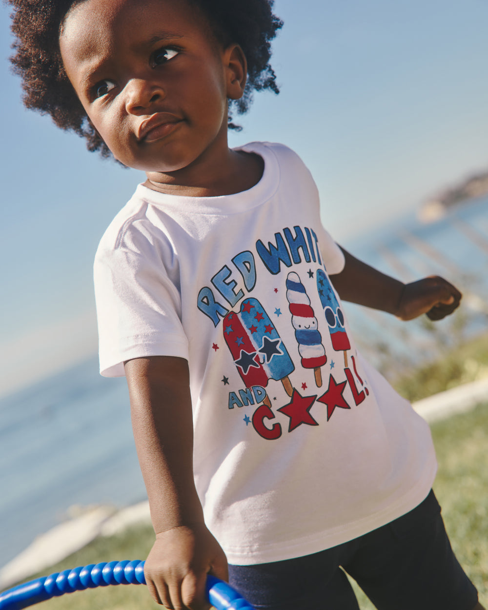 Boy wearing the Red White & Cool Relaxed Tee with the ocean in the background