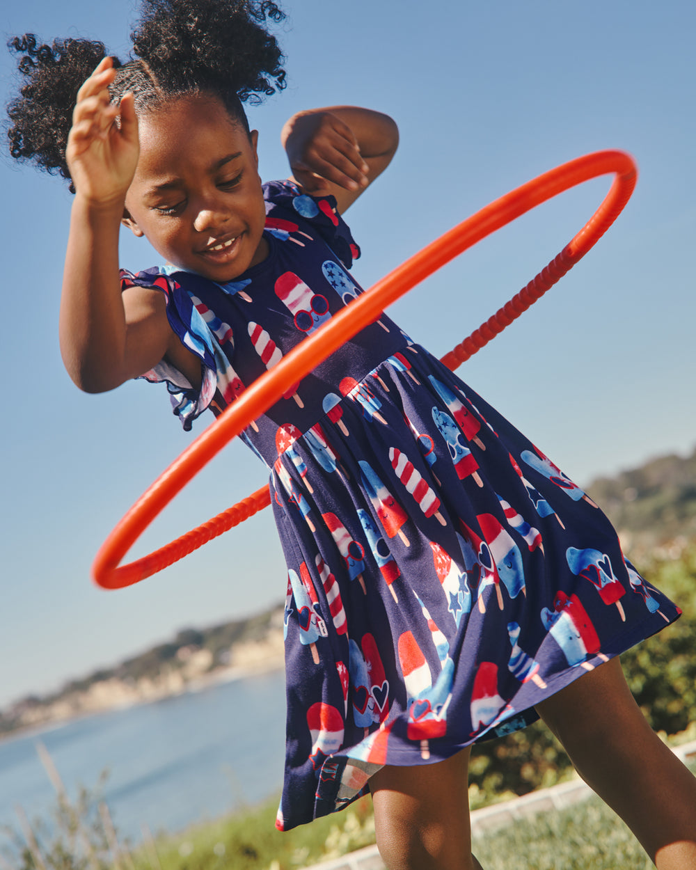 Girl playing with a hoolahoop wearing the Sparkle Treats Flutter Skater Dress