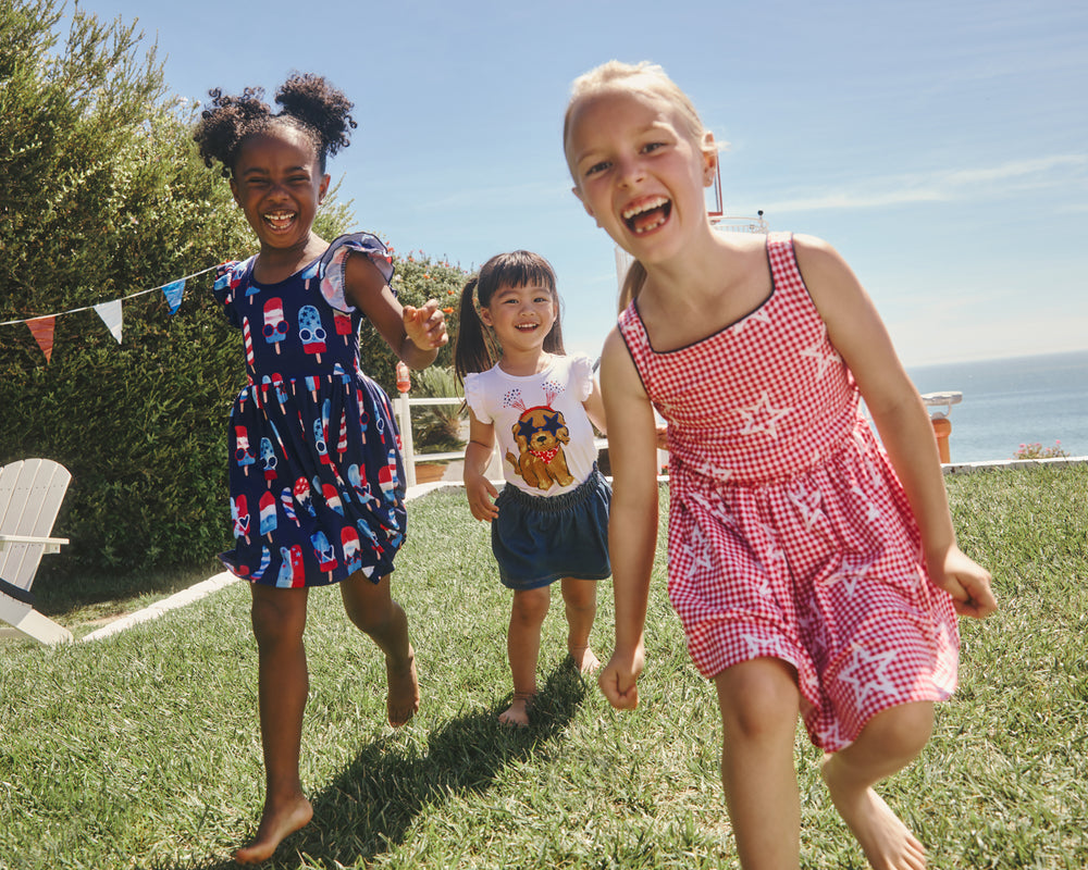 Three girls wearing 4th of July styles on a grass lawn