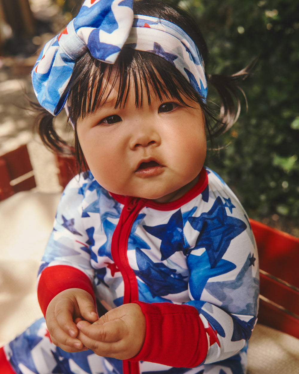 Close up of baby wearing the Starry Splash Zippy and Bow