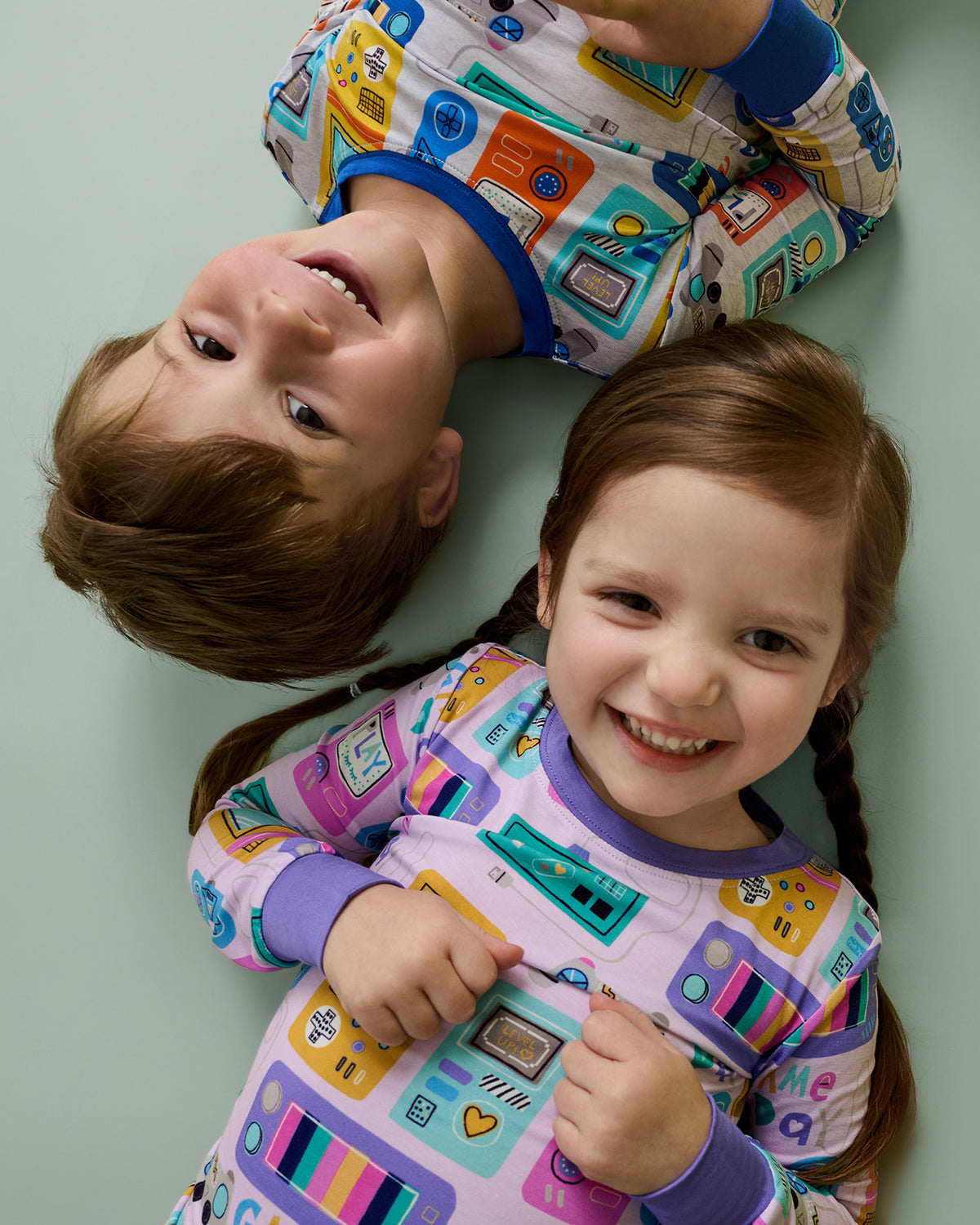 Aerial view of two children wearing Game On Two-Piece Pajama Sets