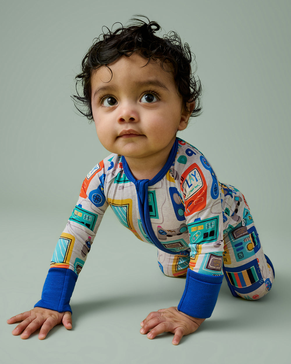 Crawling boy wearing the Game On Zippy on a green backdrop