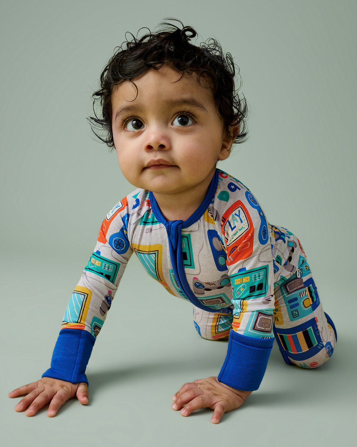 Crawling boy wearing the Game On Zippy on a green backdrop