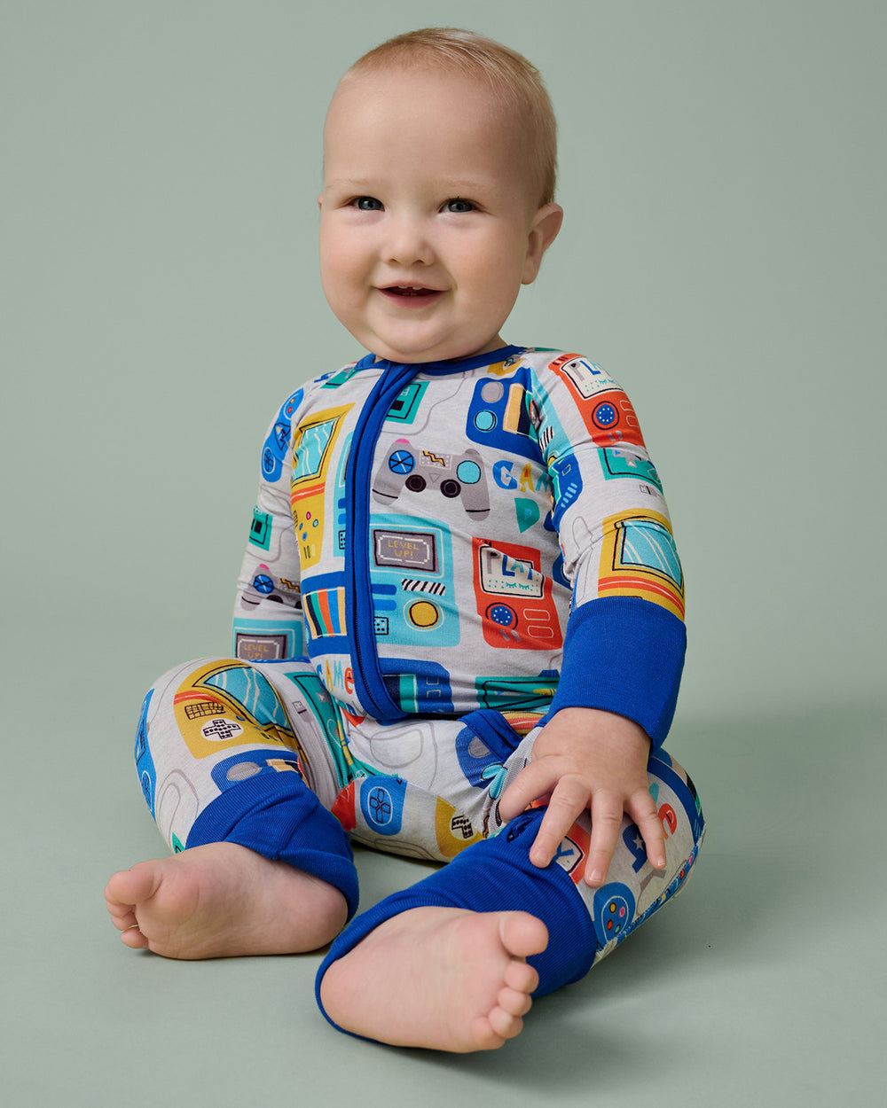 Sitting baby wearing the Game On Zippy on a green backdrop
