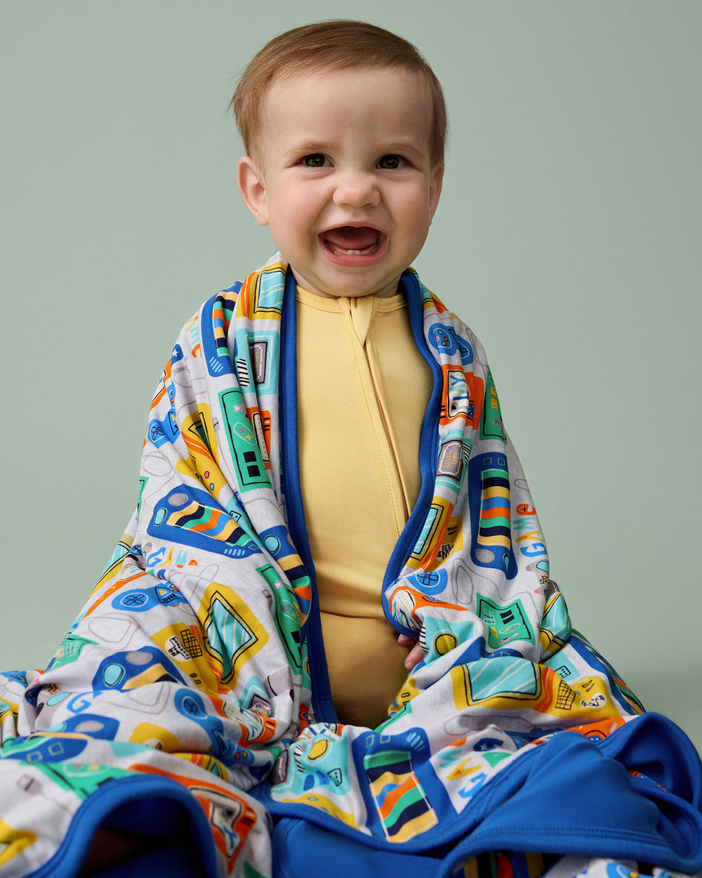 Sitting baby wrapped in the Game On Large Cloud Blanket®