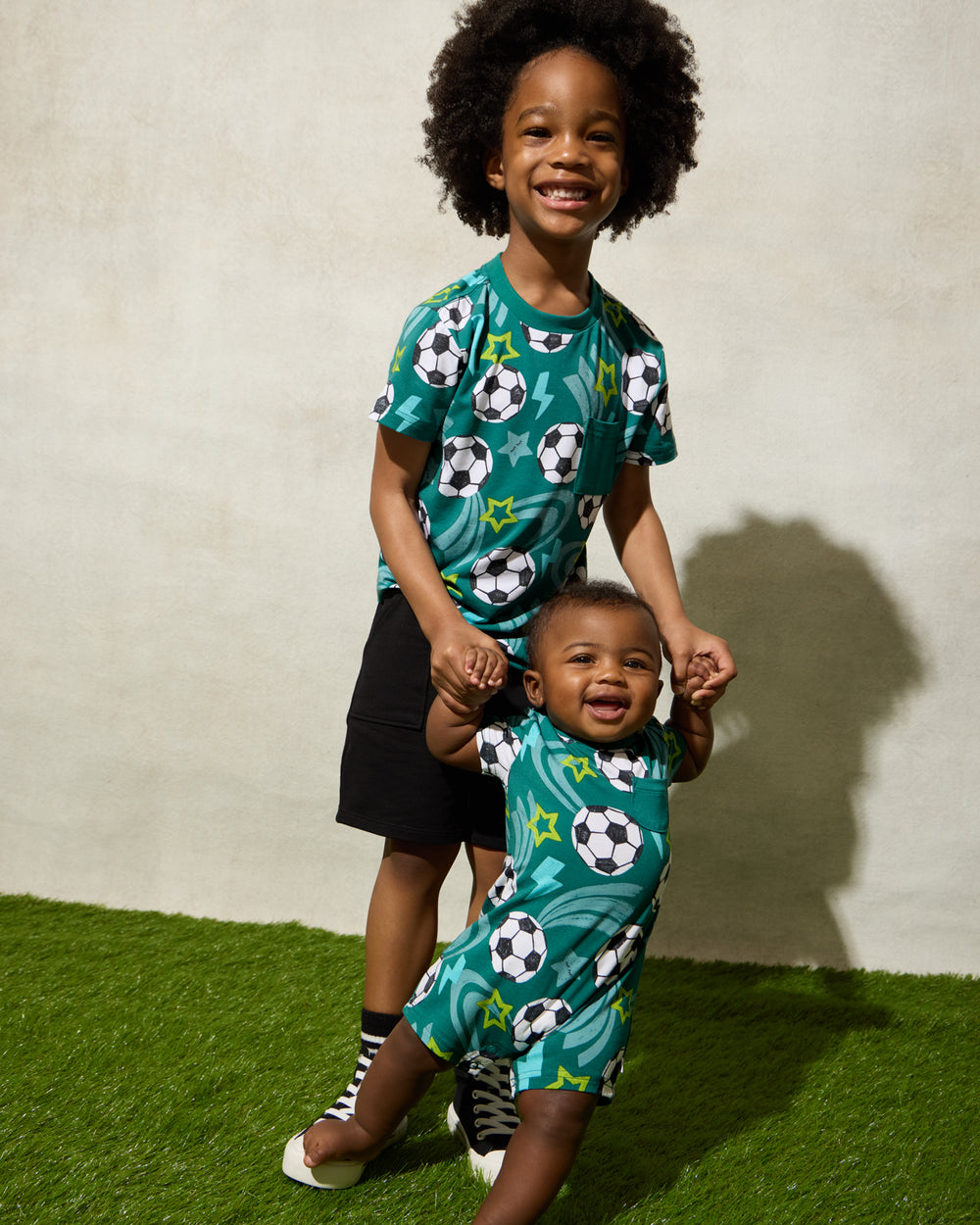 Two children wearing Soccer Stars play styles on a grassy surface