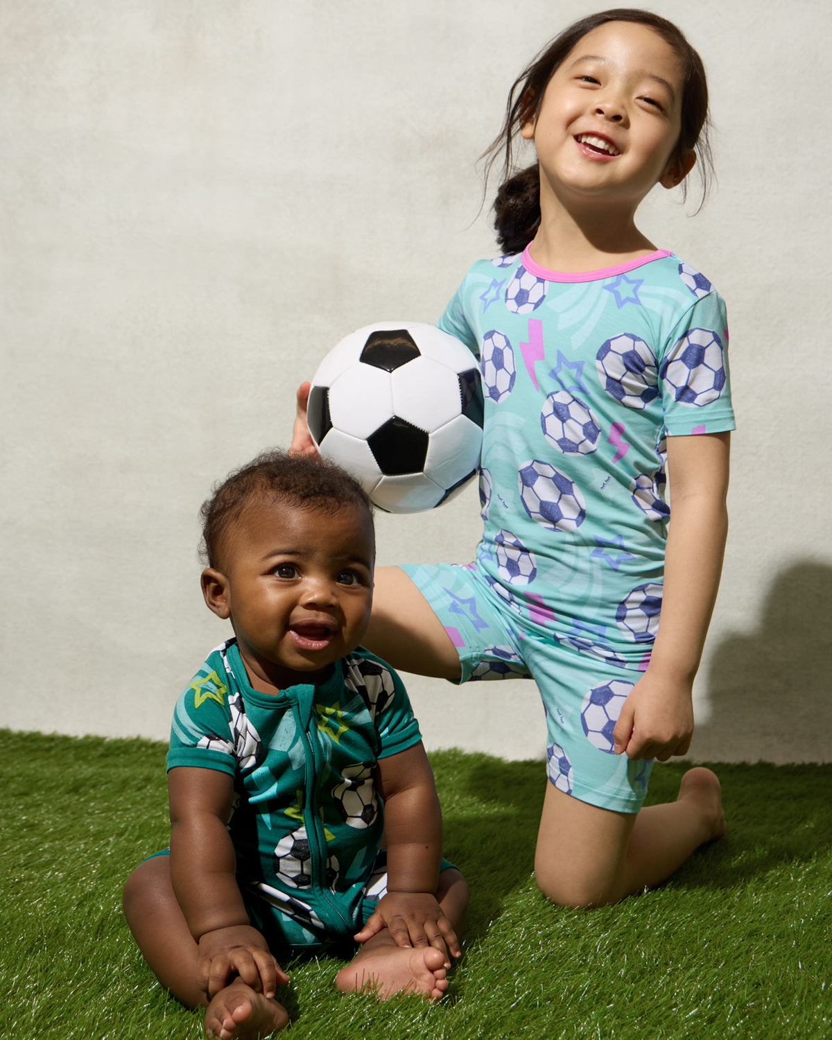 Two children wearing Soccer Stars pajamas on a grassy surface